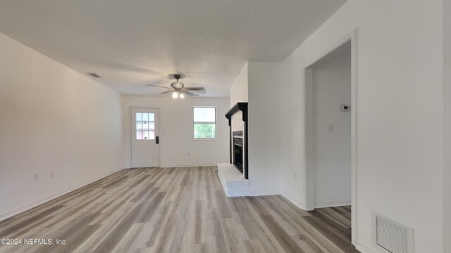 unfurnished living room featuring ceiling fan, a fireplace, and light hardwood / wood-style floors