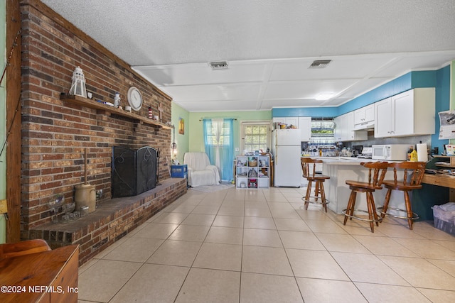 kitchen featuring white cabinetry, kitchen peninsula, a kitchen bar, a fireplace, and white appliances