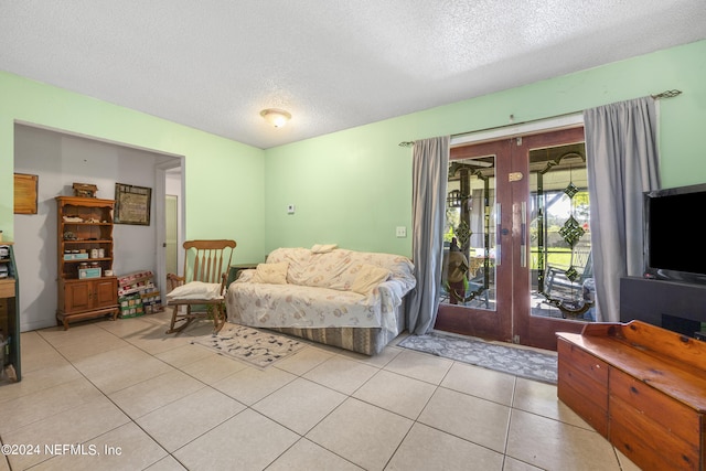 interior space with a textured ceiling, light tile patterned floors, and french doors