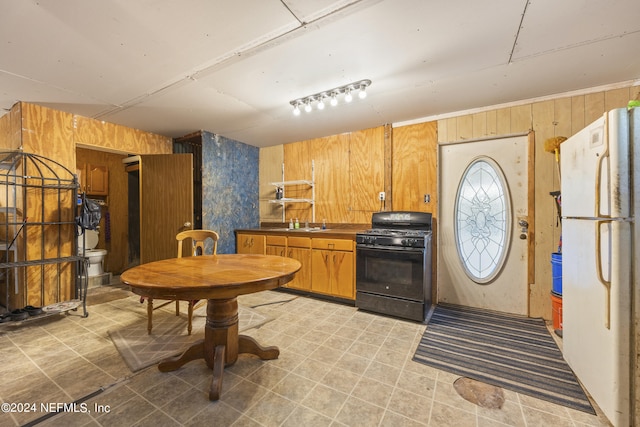 kitchen with wood walls, white fridge, and black gas range