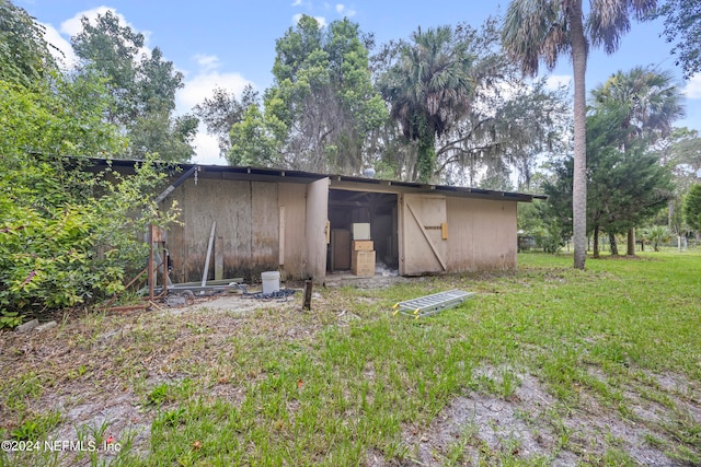 back of property featuring an outdoor structure and a yard