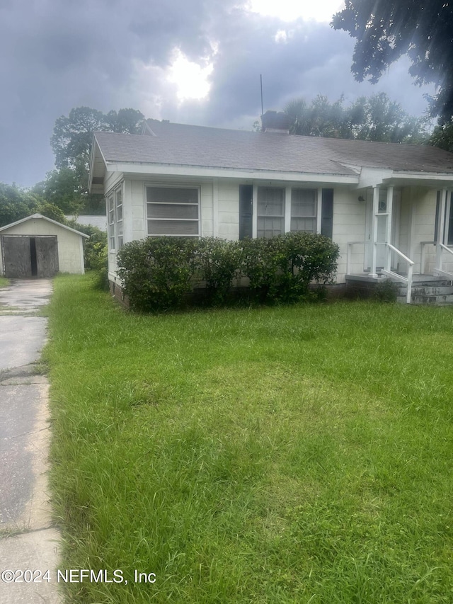 view of front of home with a front yard, an outbuilding, and driveway