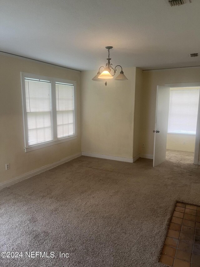 empty room with an inviting chandelier and carpet floors