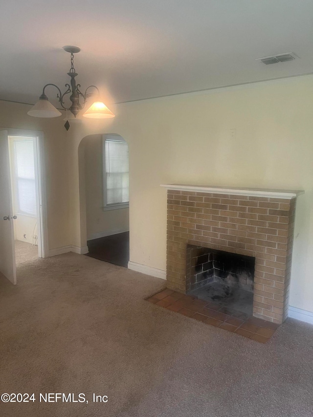 unfurnished living room with carpet, a notable chandelier, and a brick fireplace