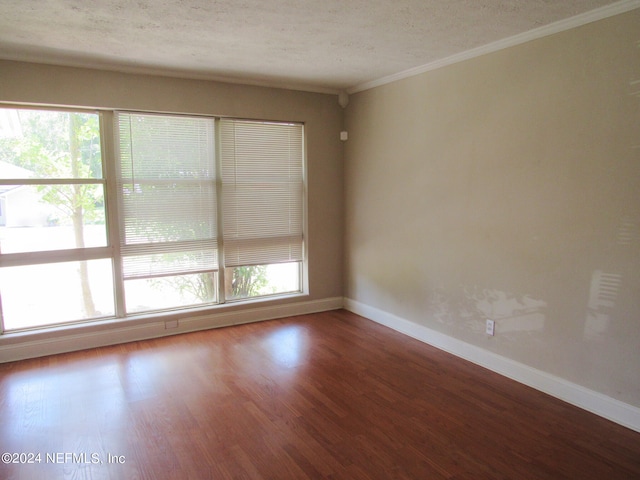 spare room with crown molding, dark wood-type flooring, and a textured ceiling