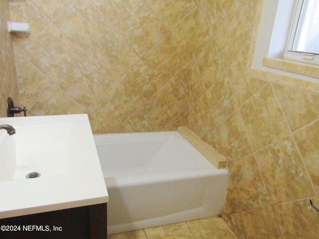 bathroom with a tub to relax in, vanity, and tile patterned flooring