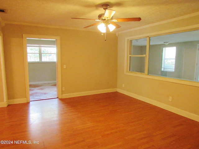 spare room featuring ceiling fan, wood-type flooring, and a healthy amount of sunlight