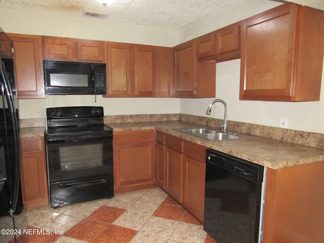 kitchen featuring black appliances, a textured ceiling, and sink