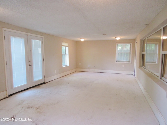 spare room featuring french doors, a textured ceiling, and plenty of natural light