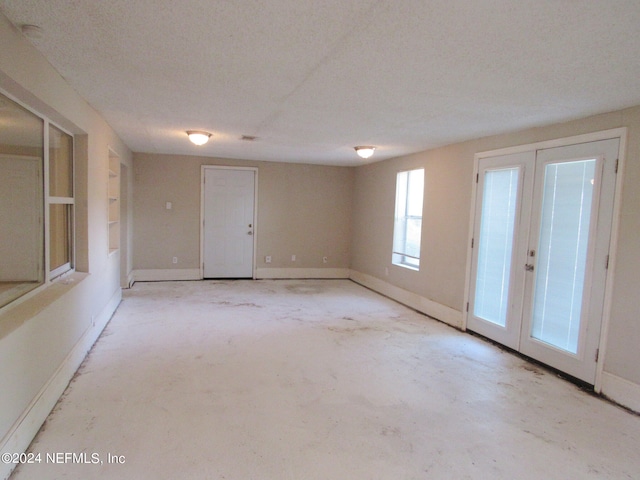 empty room with french doors and a textured ceiling