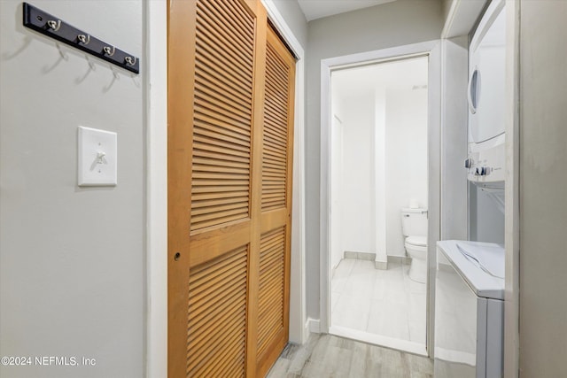 bathroom featuring toilet, hardwood / wood-style floors, and stacked washer and dryer