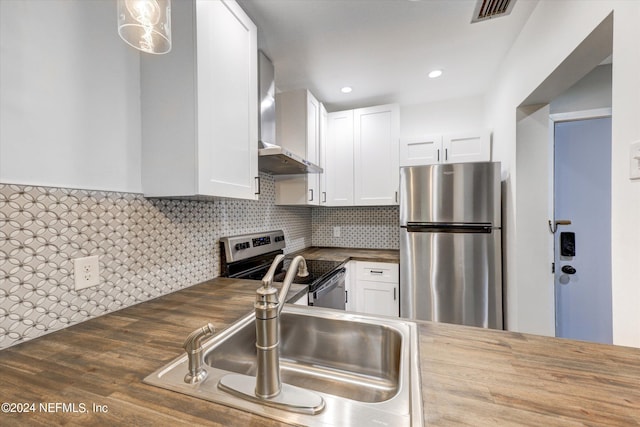 kitchen featuring wood-type flooring, stainless steel appliances, sink, wall chimney range hood, and white cabinets