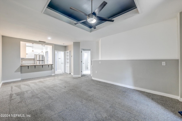 interior space featuring ceiling fan, a raised ceiling, and carpet