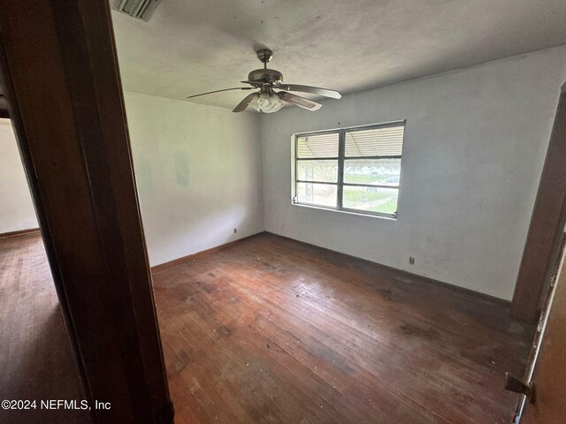 spare room with a textured ceiling, ceiling fan, and dark hardwood / wood-style floors