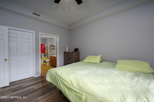 bedroom with ensuite bath, visible vents, ceiling fan, and dark wood-type flooring