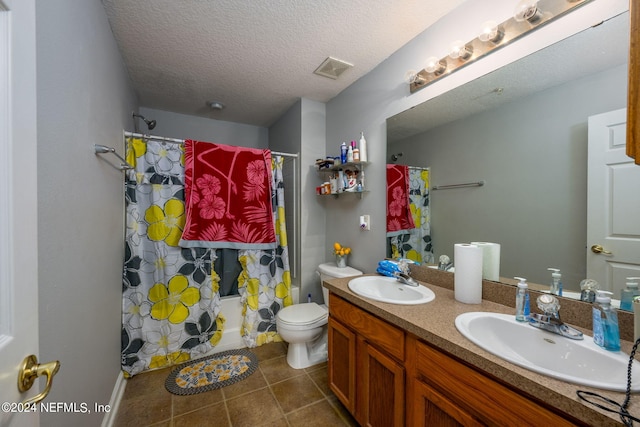 bathroom with double vanity, toilet, a sink, and a textured ceiling