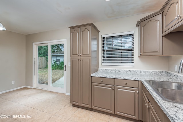 kitchen with light stone counters, light tile patterned flooring, and sink