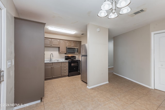 kitchen with light stone counters, stainless steel appliances, an inviting chandelier, and sink