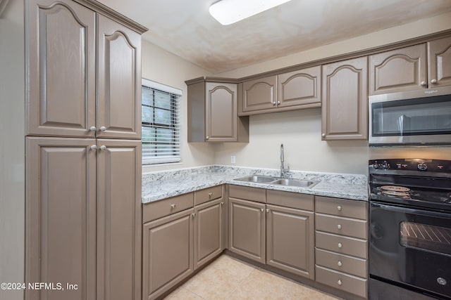 kitchen with light stone counters, light tile patterned flooring, sink, and electric range