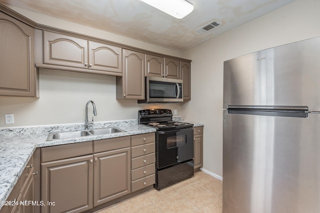 kitchen featuring light stone counters, stainless steel appliances, sink, and light tile patterned flooring