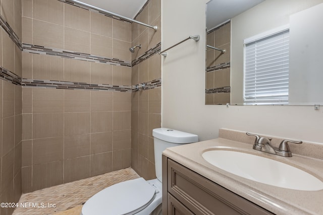 bathroom featuring vanity, toilet, and tiled shower