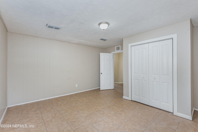 unfurnished bedroom featuring a textured ceiling and a closet