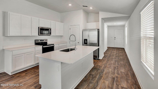 kitchen with an island with sink, appliances with stainless steel finishes, vaulted ceiling, white cabinetry, and a sink