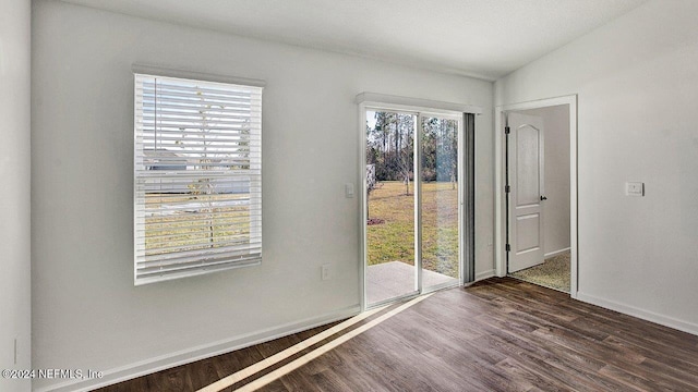 empty room featuring baseboards, vaulted ceiling, and wood finished floors