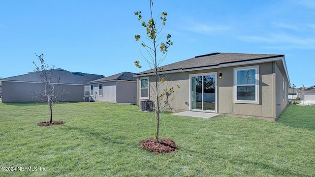 rear view of house with stucco siding, a yard, and central AC unit