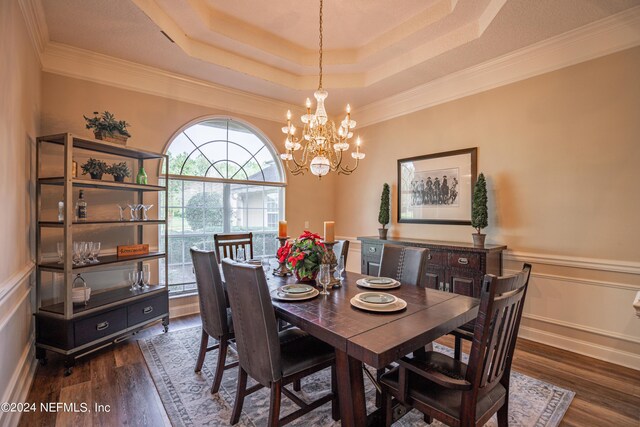 dining space featuring dark hardwood / wood-style floors, ornamental molding, a tray ceiling, and a notable chandelier