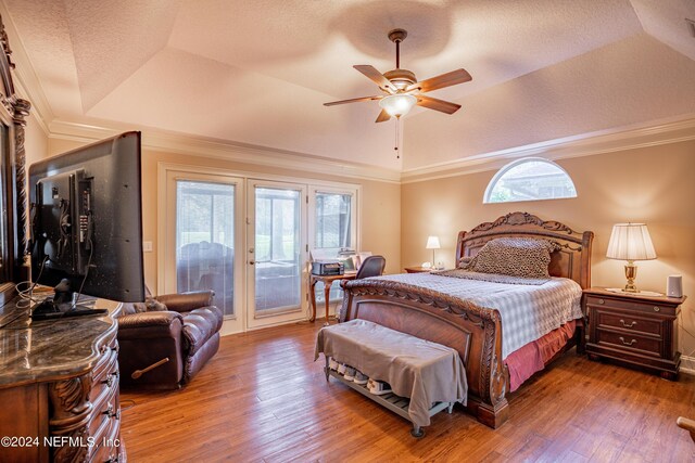 bedroom featuring hardwood / wood-style flooring, a tray ceiling, ornamental molding, a textured ceiling, and access to outside