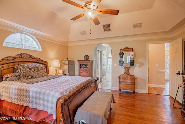 bedroom featuring crown molding, ceiling fan, hardwood / wood-style floors, a tray ceiling, and vaulted ceiling