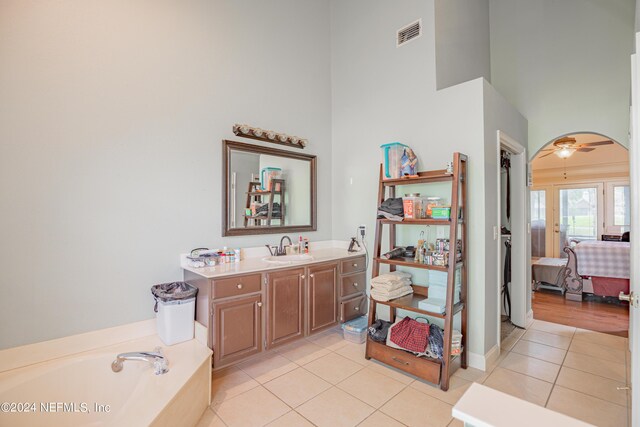 bathroom with tile patterned floors, a high ceiling, vanity, and a tub