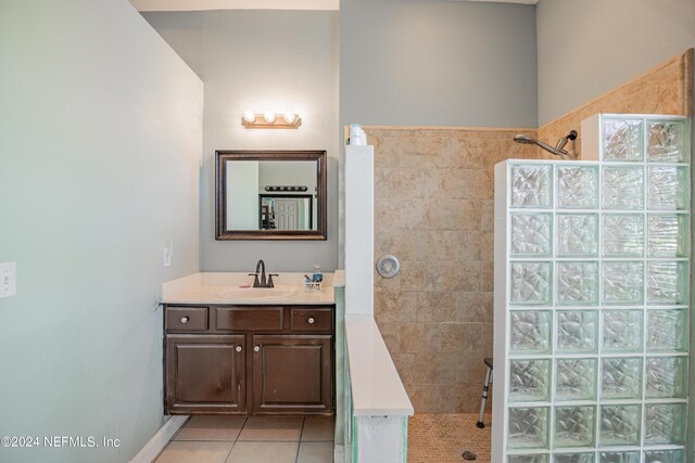 bathroom with tile patterned floors, vanity, and a tile shower