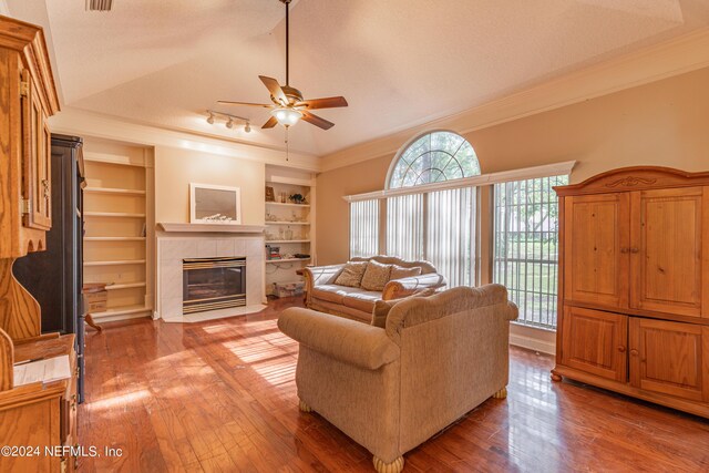 living room with built in shelves, ornamental molding, a textured ceiling, and hardwood / wood-style flooring