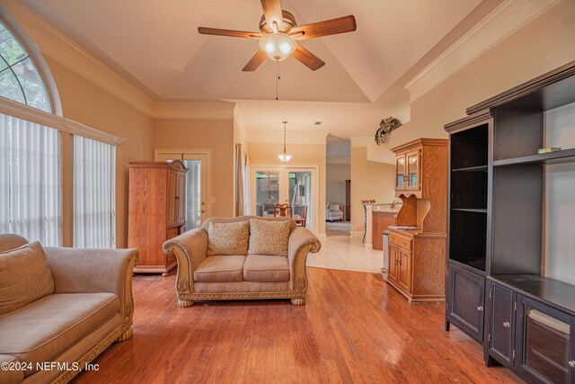 living room with lofted ceiling, hardwood / wood-style flooring, ornamental molding, and ceiling fan