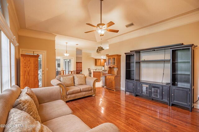 living room with crown molding, ceiling fan, a tray ceiling, dark hardwood / wood-style flooring, and vaulted ceiling