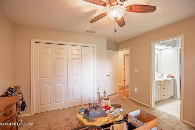 interior space with ceiling fan, light colored carpet, and a textured ceiling