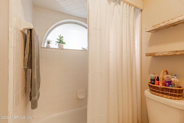 bathroom featuring shower / tub combo with curtain and toilet