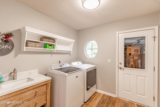 laundry area featuring independent washer and dryer, sink, a textured ceiling, and light wood-type flooring