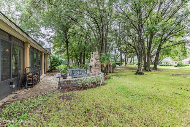 view of yard with a patio and an outdoor stone fireplace