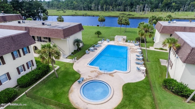 view of swimming pool featuring a water view, a yard, and a patio area