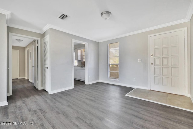 foyer entrance with baseboards, visible vents, crown molding, and wood finished floors