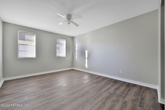empty room featuring a ceiling fan, dark wood-type flooring, and baseboards
