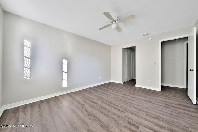 unfurnished bedroom featuring baseboards, visible vents, a ceiling fan, a closet, and wood finished floors