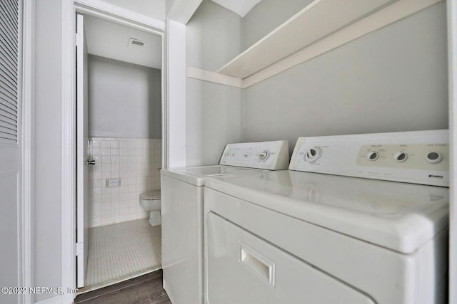 laundry area with washer and clothes dryer, wainscoting, laundry area, visible vents, and tile walls