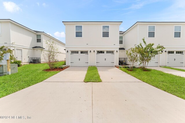 front of property featuring a front yard, cooling unit, and a garage