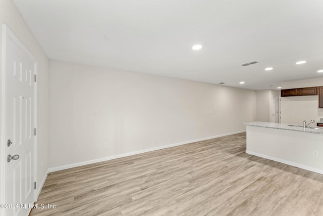 unfurnished living room featuring sink and light hardwood / wood-style floors