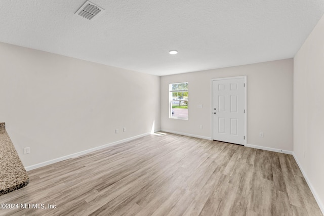 unfurnished room with a textured ceiling and light wood-type flooring