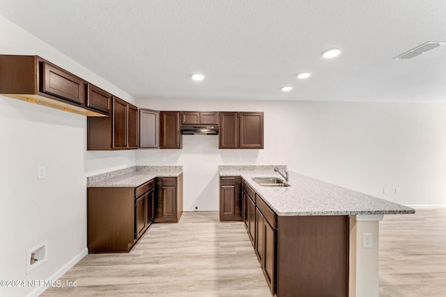 kitchen with dark brown cabinets, a textured ceiling, light hardwood / wood-style floors, and sink